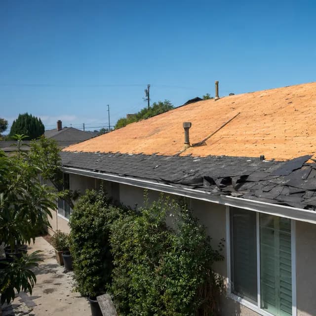 Wide view of a suburban roof mid tear-off with stripped shingles and bare deck
